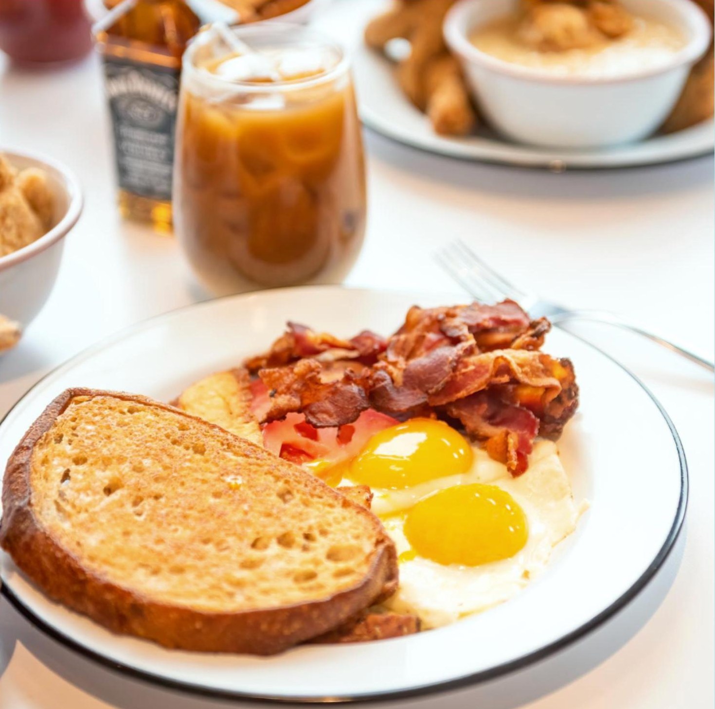 CHIX classic breakfast with toast, two eggs and bacon, next to an iced coffee