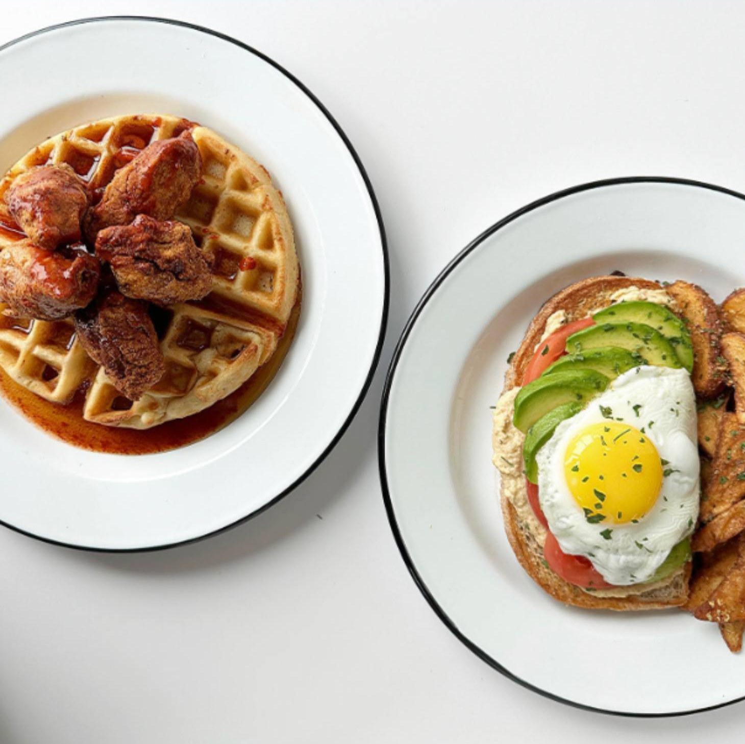 Chicken and waffles next to avocado toast with a sunny-side egg on CHIX enamel plates